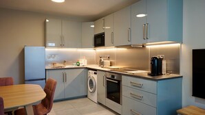 A modern kitchen with a built-in washing machine, a microwave, and a coffee machine. - Freshly Refurbished 2BD Flat in Catford Bridge (Greater London)