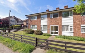 A two-story residential building with a brick facade, white window frames, and a front garden with a wooden fence. - Freshly Refurbished 2BDR Flat in Catford Bridge (Greater London)