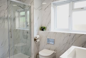 Ein Badezimmer mit einer Duschkabine, einer Toilette und einem Waschbecken.