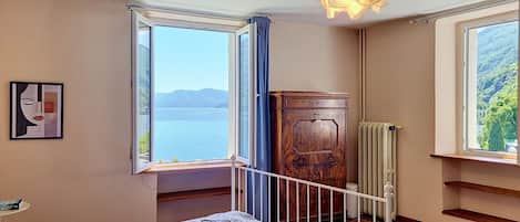 Un dormitorio con cama, vista al mar, un radiador y un armario de madera.