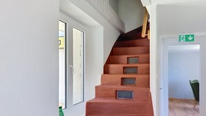 A staircase with a wooden handrail and a green emergency exit sign. - Casa Yakamos by Interhome (Brissago)