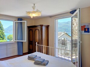 Une chambre à coucher avec un lit, une armoire en bois, une fenêtre avec des rideaux et une vue sur un paysage montagneux.
