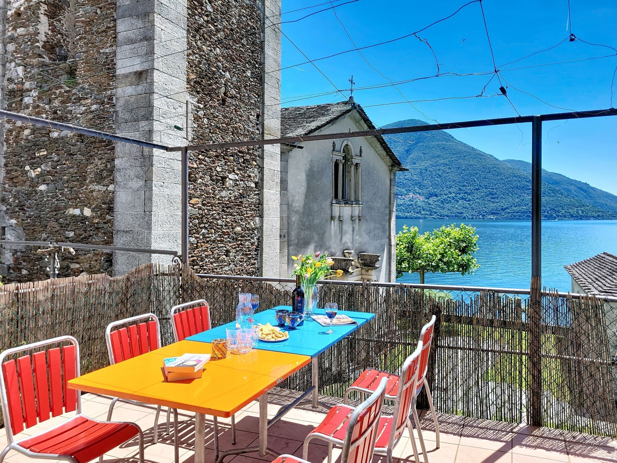 An outdoor dining area with a table and chairs, overlooking a lake and a mountain.