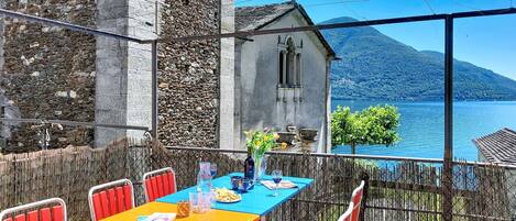 An outdoor dining area with a table and chairs, overlooking a lake and a mountain.