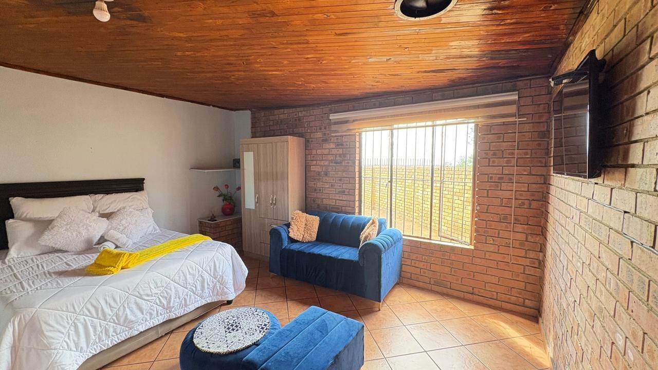 Un dormitorio con una cama, un sofá azul, una mesita y una ventana con vistas.