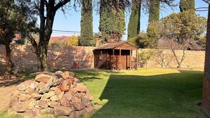 Un patio trasero con un cobertizo de madera, un muro de piedra y un césped.
