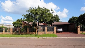Propiedad residencial con puerta de acceso, garaje, muros de ladrillo y camino de entrada pavimentado.