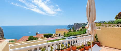 Une terrasse avec vue sur la mer, des meubles d’extérieur et des plantes en pot.