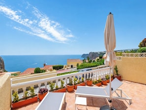 Une terrasse avec vue sur la mer, des meubles d’extérieur et des plantes en pot.