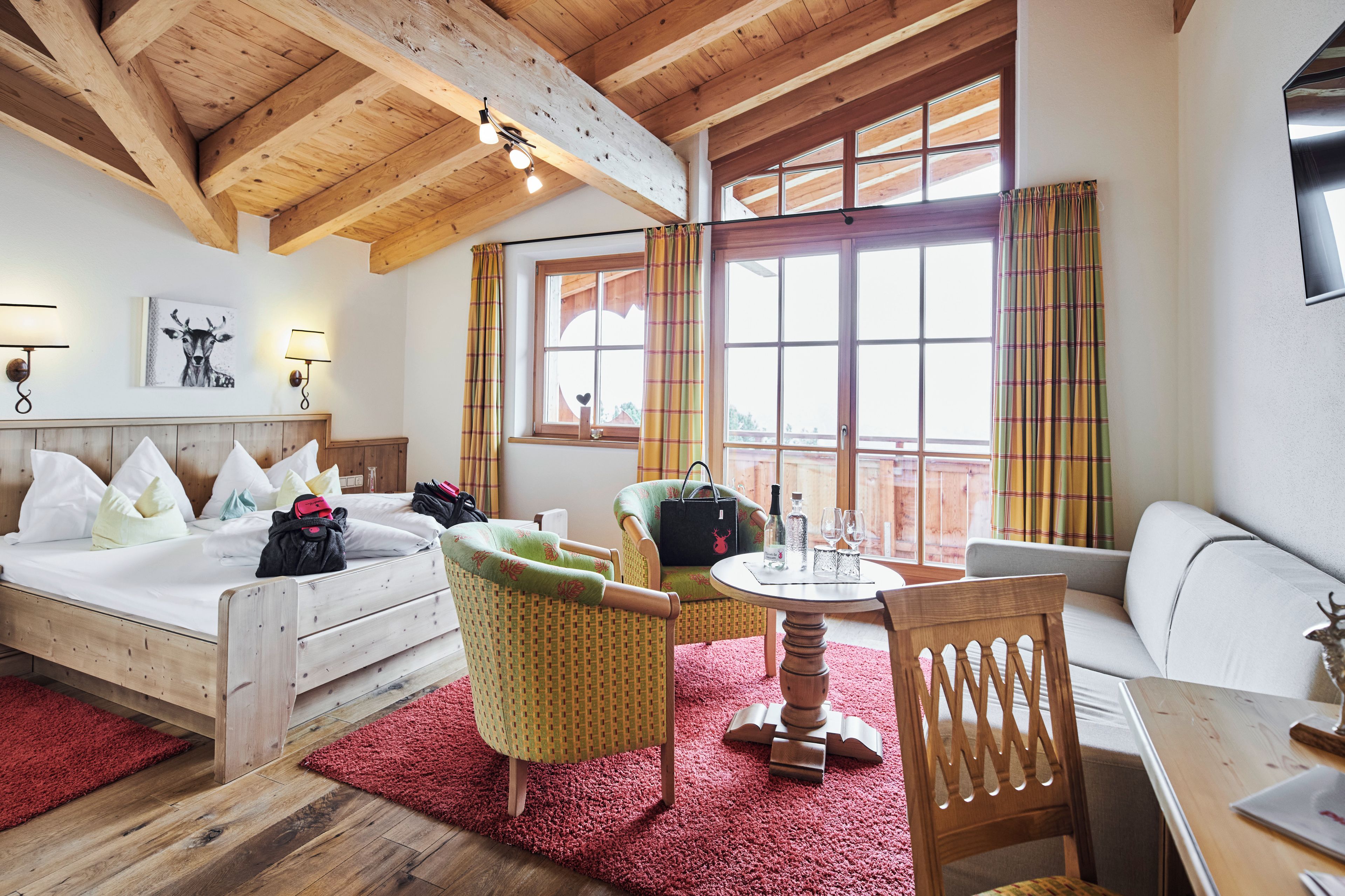 Een kamer met een bed, een stoel, een tafel en een raam met gordijnen.