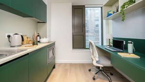 Une petite cuisine avec une fenêtre, un ordinateur portable et une chaise.
