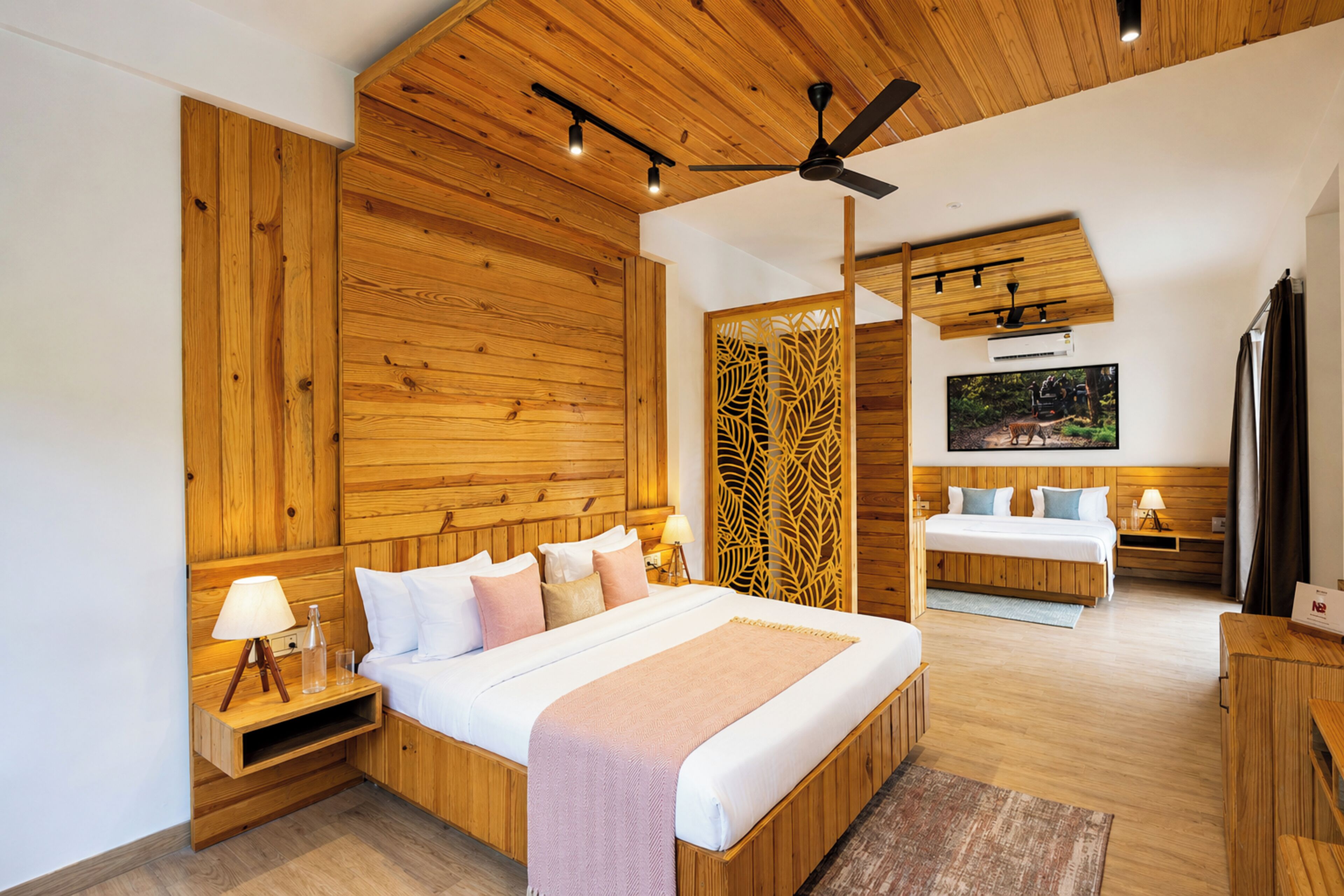 A modern bedroom with a large bed, a ceiling fan, and wooden paneling.