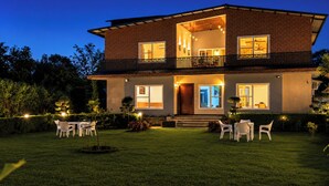 Una casa a due piani con un balcone, un portico e un ingresso ben illuminato.