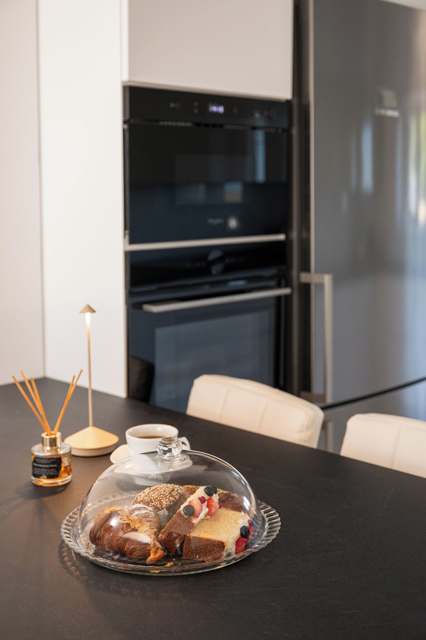 Una cocina moderna con una mesa de comedor, una taza de café y una presentación de postres.