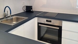 Una cuina moderna amb un rentaplat de coure, un forn integrat i un televisor de pantalla plana penjat a la paret.
