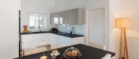A modern kitchen with white cabinets, a black countertop, and a dining area with a table set for two.