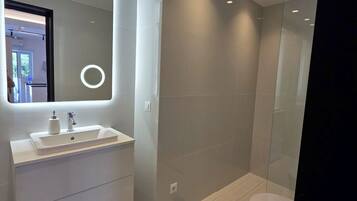 A modern bathroom with a large mirror, a white sink, and a toilet.