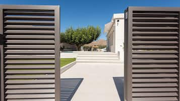Un chemin menant à un bâtiment à l’architecture moderne, avec un ciel dégagé et un arrière-plan bordé d’arbres.