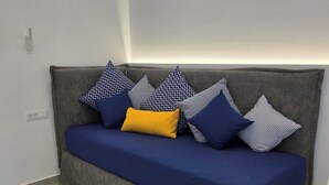 Un sofà gris amb una funda blava i molcalçaments amb diferents motius.