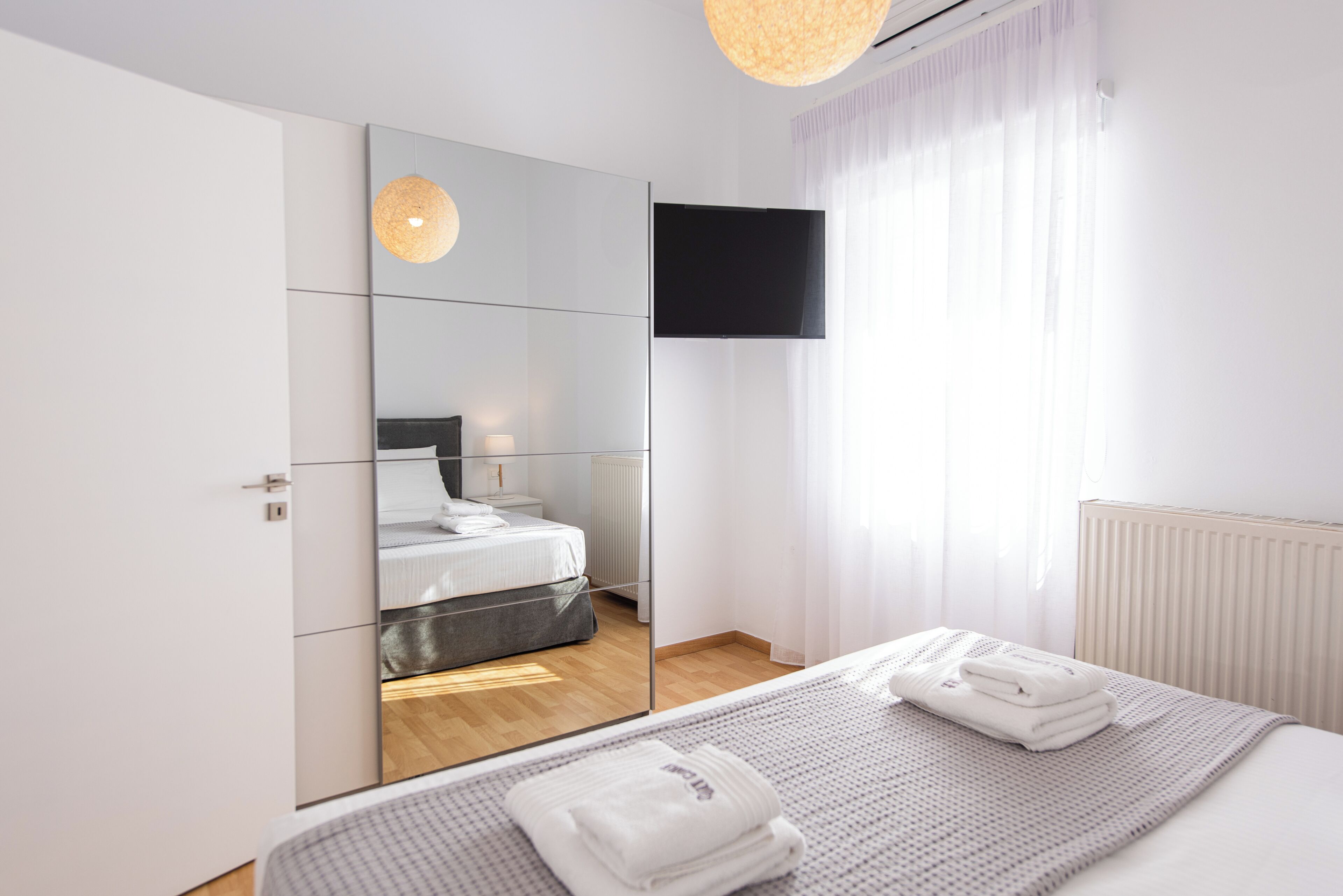 A modern bedroom with a bed, a television, and a mirror.