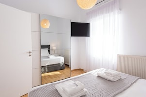 Un dormitorio moderno con cama, televisión y espejo.