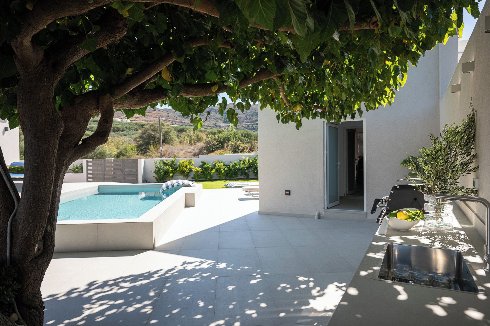 Zona de piscina exterior con un árbol que ofrece sombra, un lavabo integrado y vistas del paisaje circundante.