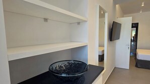 A modern hotel room with a black countertop, a glass bowl, and a flat-screen TV mounted on the wall. - Azure West by Cozy Corner (Ag. Georgios)