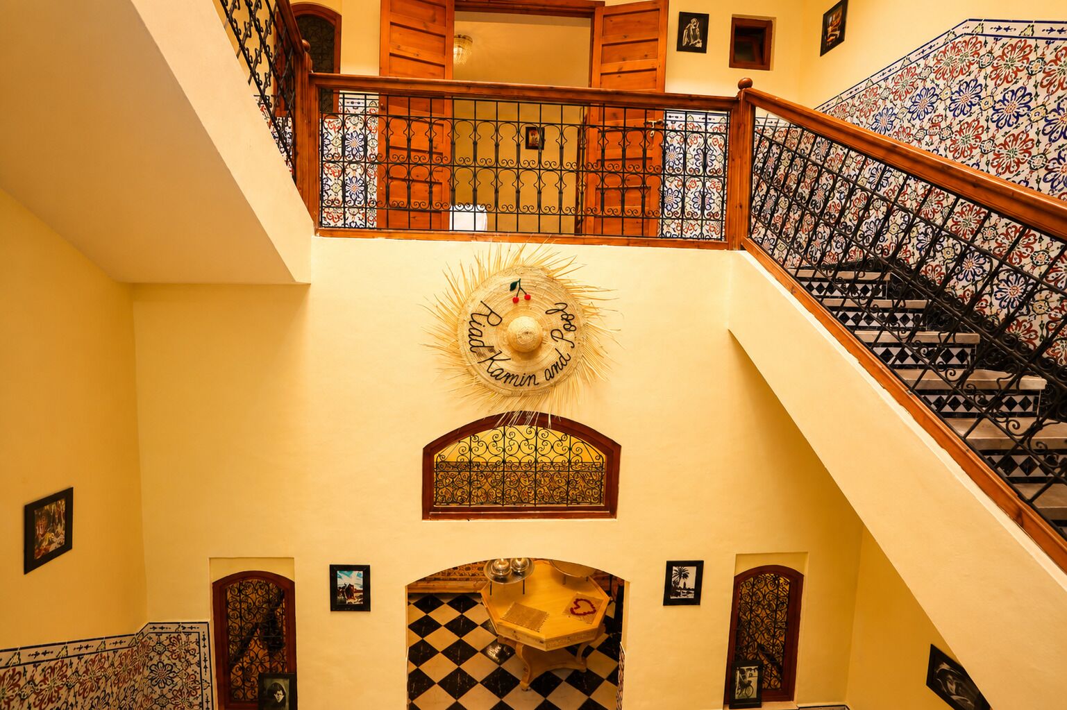 A multi-level interior with a staircase, decorative wall art, and patterned tiles.