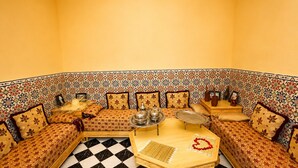 A corner room with patterned sofas, a checkered floor, and a central table with a tray and decorative items. - Riad Kamin And Pool (Marrakech)
