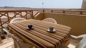 A balcony with a table and chairs, a view of the landscape, and a clear sky. - HostySpot - Tropical Resort, 1-Bedroom Apartment (Santa Maria)
