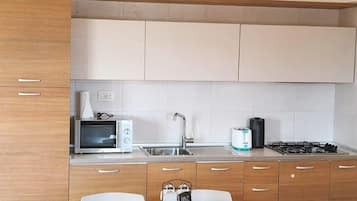 A modern kitchen with a dining table, chairs, a ceiling fan, a microwave, a toaster, and a gas stove.
