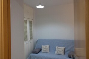 A room with a blue sofa, two pillows with text, a white wardrobe, and a hanging light fixture. - Aguilas Center & Costa, with Balcony, Wi-Fi and Air Conditioning (Aguilas)