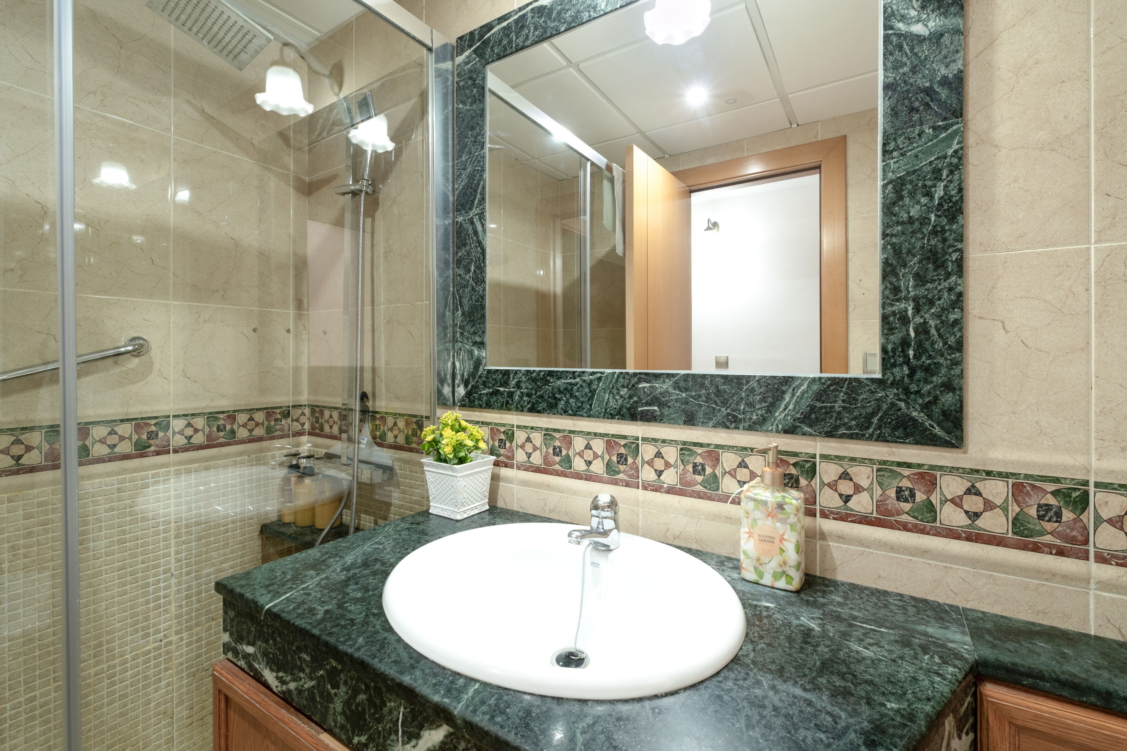 A bathroom with a marble sink, a large mirror, and a shower area.