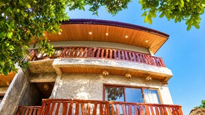 Un edificio de varios pisos con techo curvo, balcones con barandillas de madera y ventanas grandes.