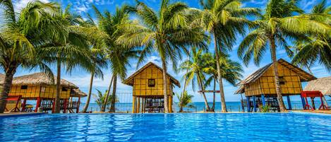 A swimming pool with overwater bungalows and palm trees.