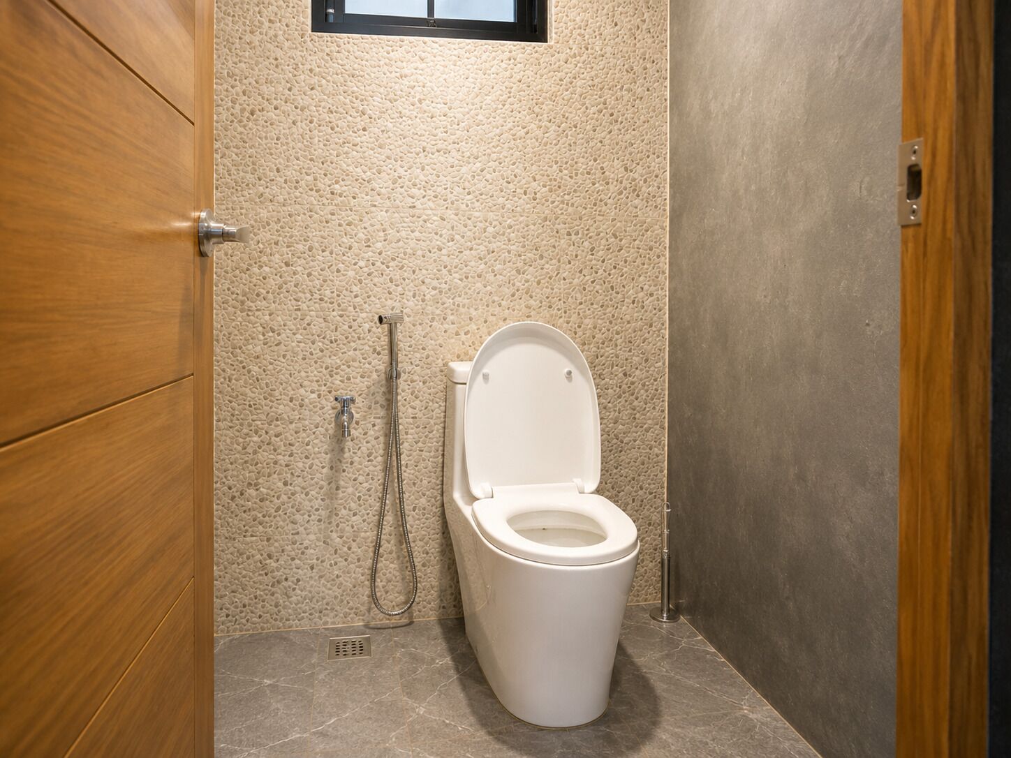 A bathroom with a toilet, shower, and a wooden door.