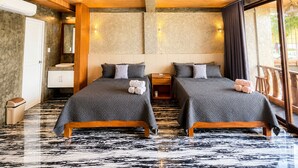 Habitación de hotel con dos camas, baño y balcón con vistas.