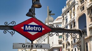 A metro sign with 'Metro' and 'Gran Via' text, attached to a metal structure with a decorative element.