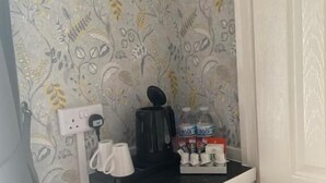 A kitchenette with a coffee maker, a water dispenser, and a set of cups on a counter. - The Woodleigh Hotel (Blackpool)