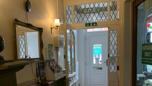 A hotel hallway with a patterned carpet, a reception desk, a fire extinguisher, and a door with a sign indicating 'Entrance Only'. - The Woodleigh Hotel (Blackpool)