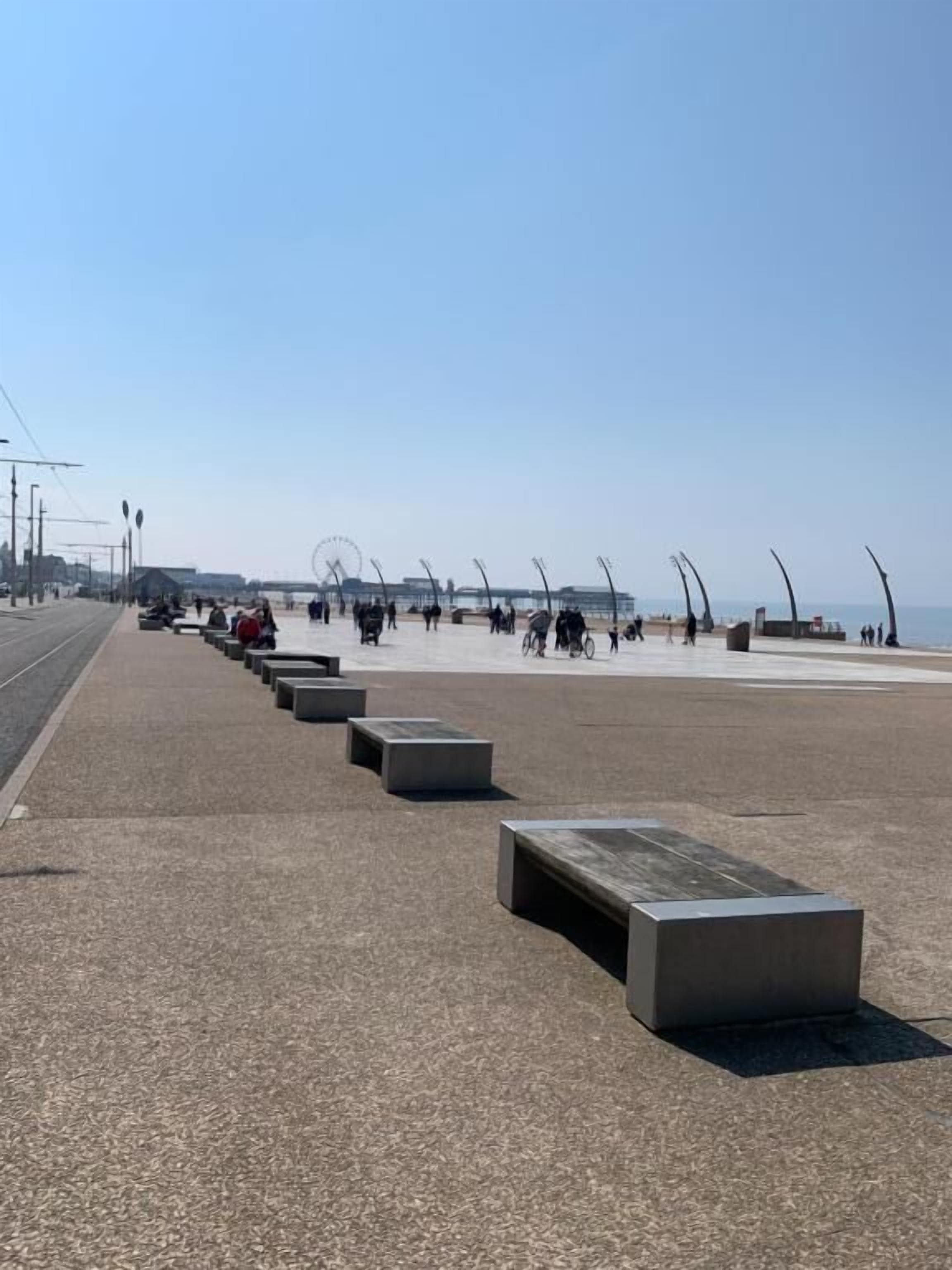 A wide promenade with benches and a clear sky.