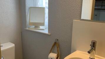 Un bany amb vàter, un lavabo i una finestra amb cortina.