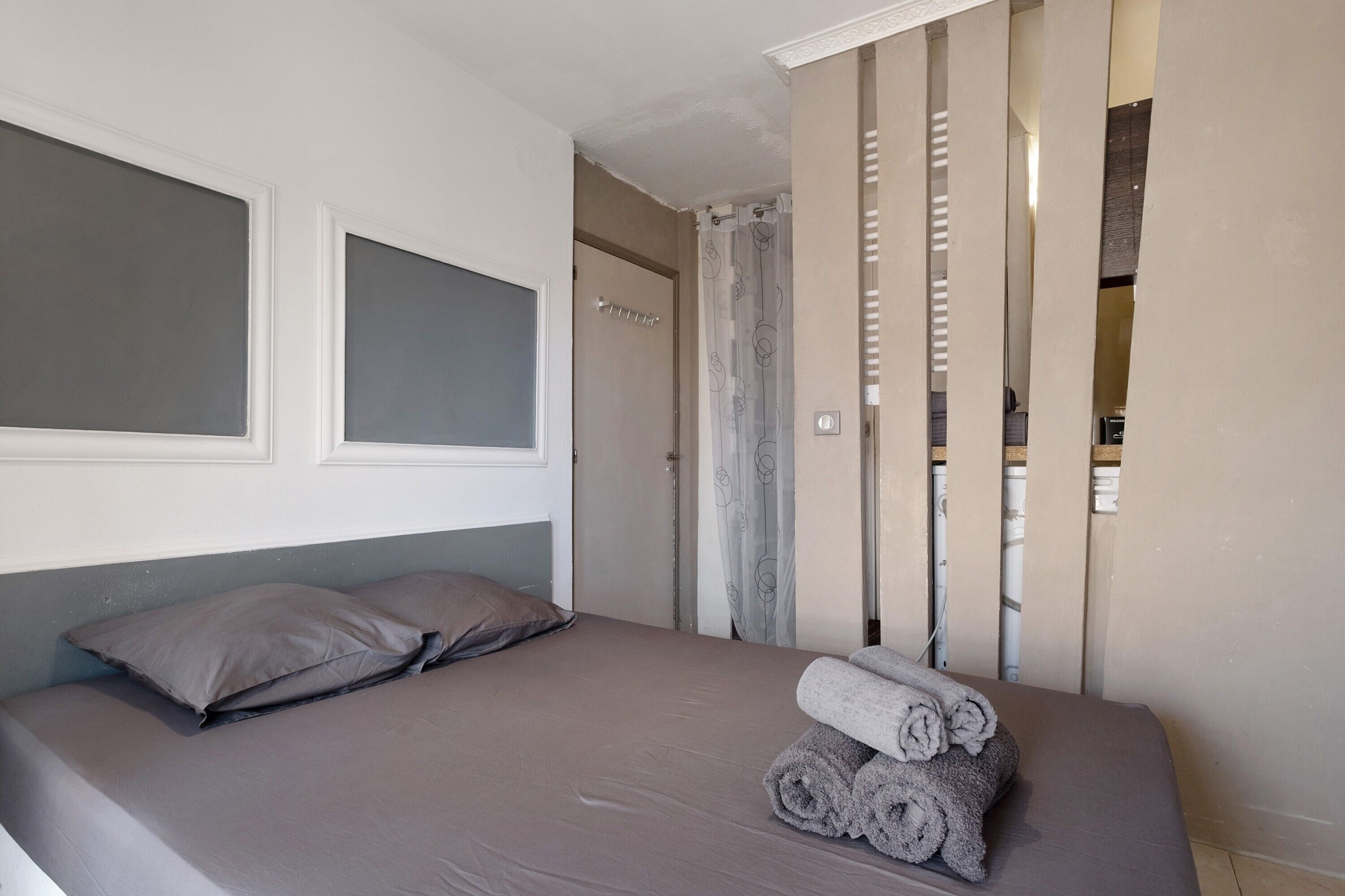 Een slaapkamer met een bed, een kussen, een handdoek en een gordijn.