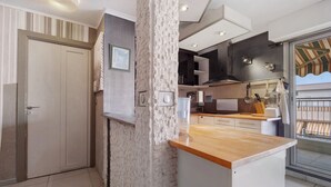 A modern kitchen with a stone accent wall, a wooden countertop, and a view of the balcony.