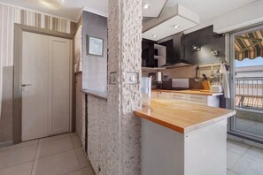 A modern kitchen with a stone accent wall, a wooden countertop, and a view of the balcony.
