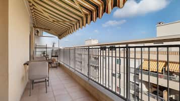 Un balcon avec un auvent à rayures, une chaise et une table.