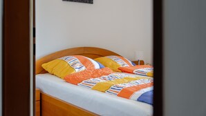 Ein Bett mit Holz Kopfteil, weißer Bettwäsche und bunten Kissen.