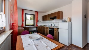 Eine kleine Küche mit Holzausstattung, einem eingebauten Backofen und einem Kühlschrank.