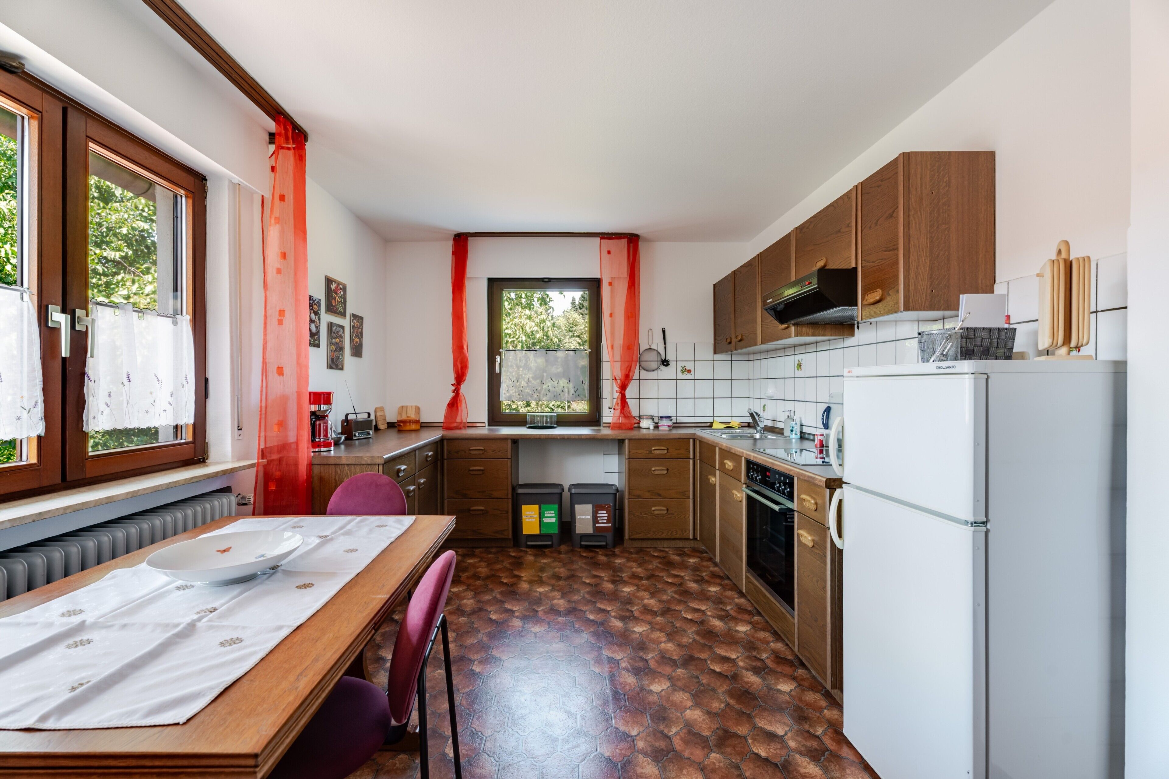 Une cuisine compacte avec des meubles en bois, un four encastré et un coin repas comprenant une table et des chaises.