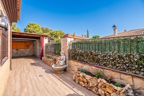 A courtyard with a stone wall, a Buddha statue, and a pergola. - Cubo's Buddha Harmony House / Private pool / Air conditioning / BBQ / Free Wi-Fi (Pizarra)